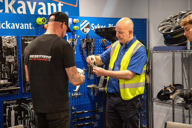 Two men looking at pullers at sykes pickavant hq with tools and equipment around.