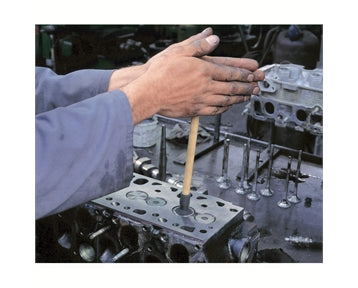 image shows a valve grinding stick being used on an engine